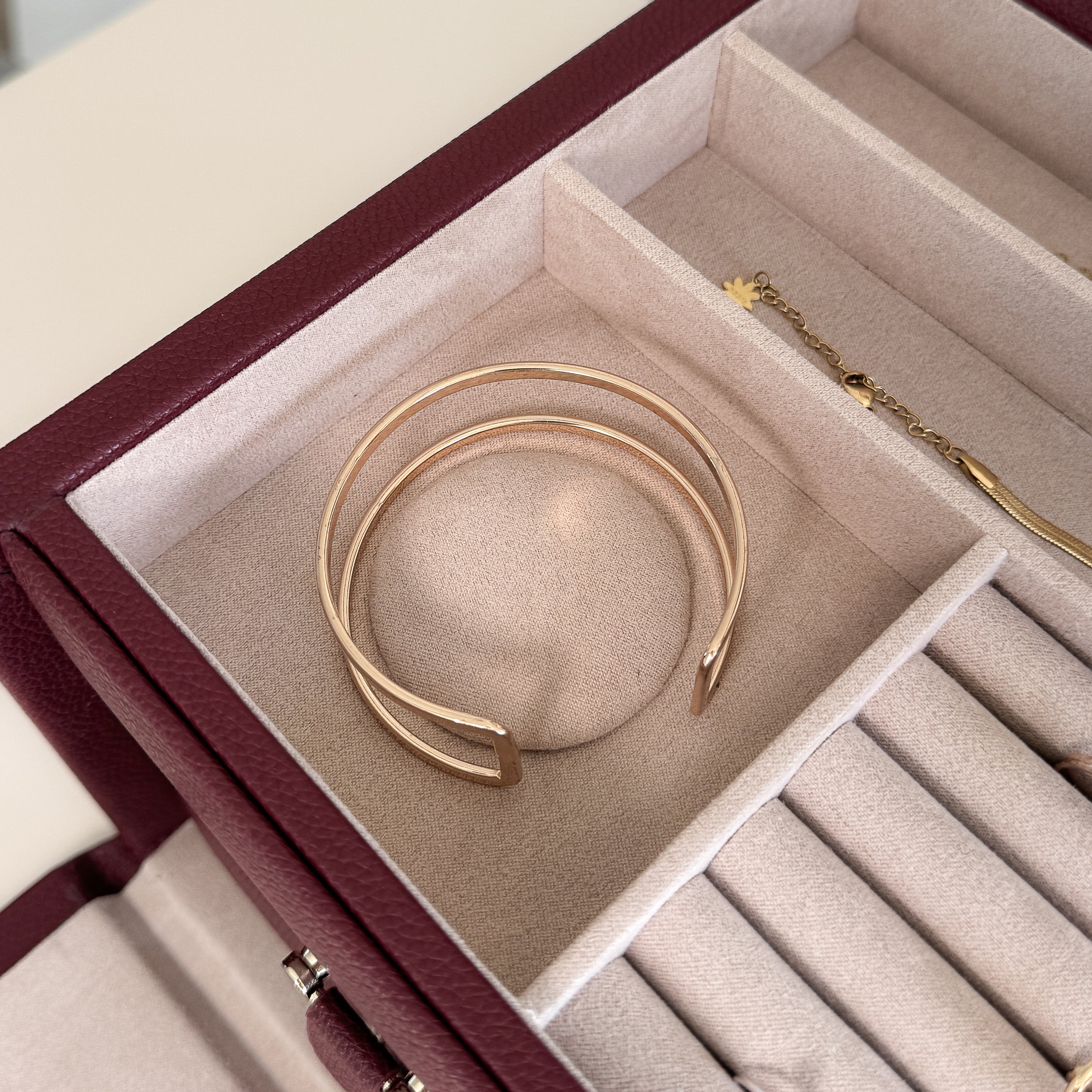 Grande boîte à bijoux en cuir bordeaux de la collection Vitoria. Vue ouverte, remplie de bijoux avec un zoom sur un bracelet de type jonc