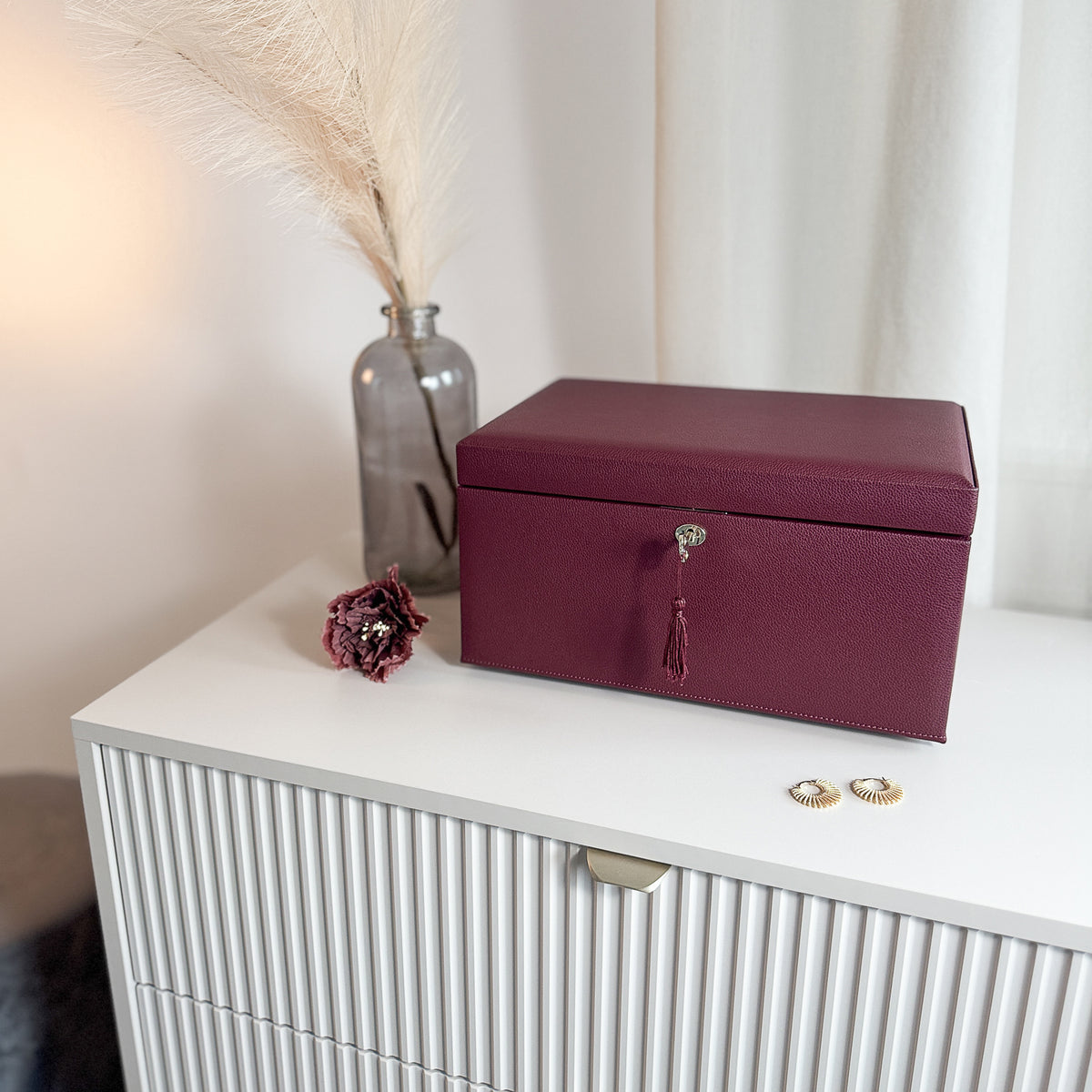 Grande boîte à bijoux en cuir bordeaux de la collection Vitoria. Vue fermée, posée sur une commode