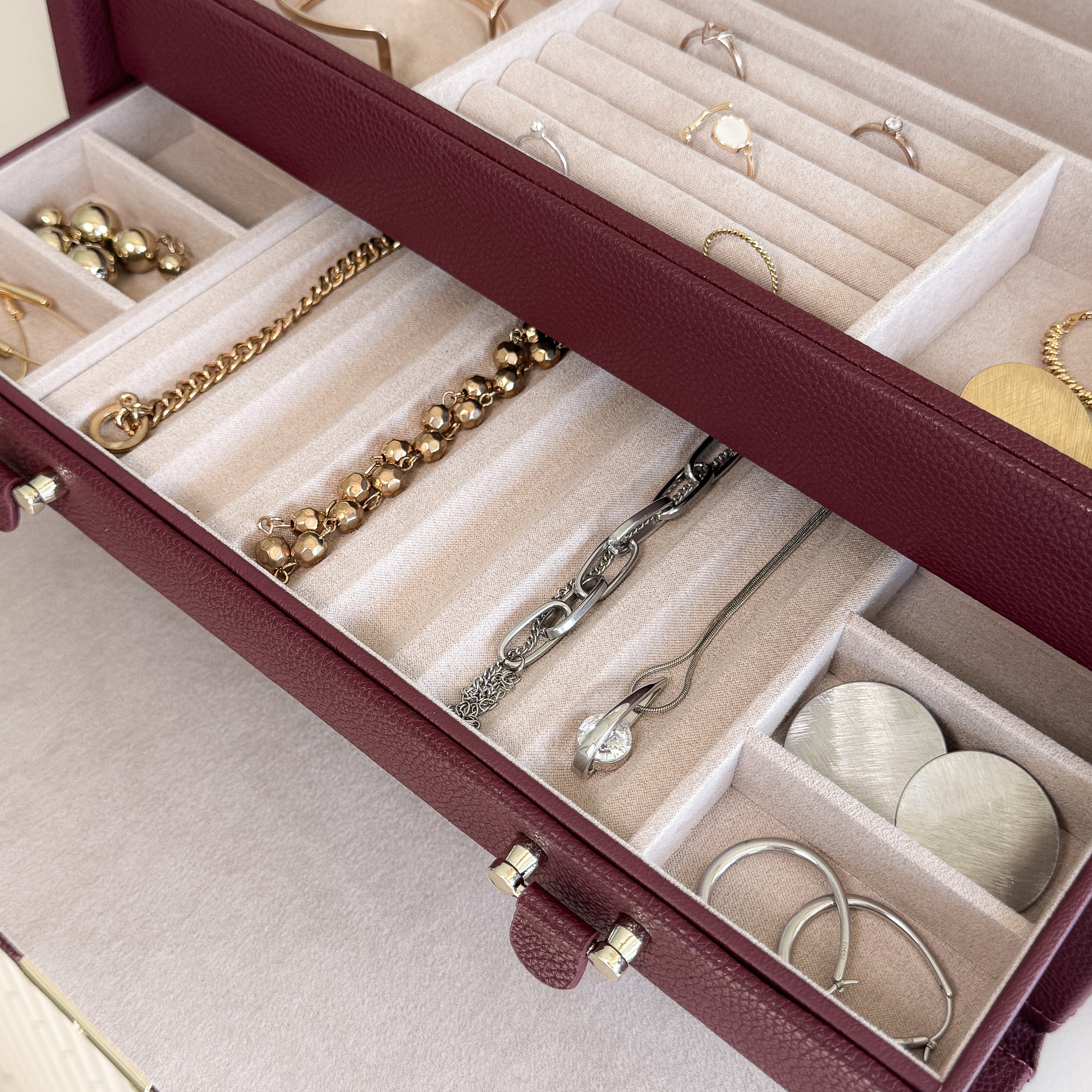 Grande boîte à bijoux en cuir bordeaux de la collection Vitoria. Vue ouverte, remplie de bijoux avec un zoom sur le tiroir à bijoux