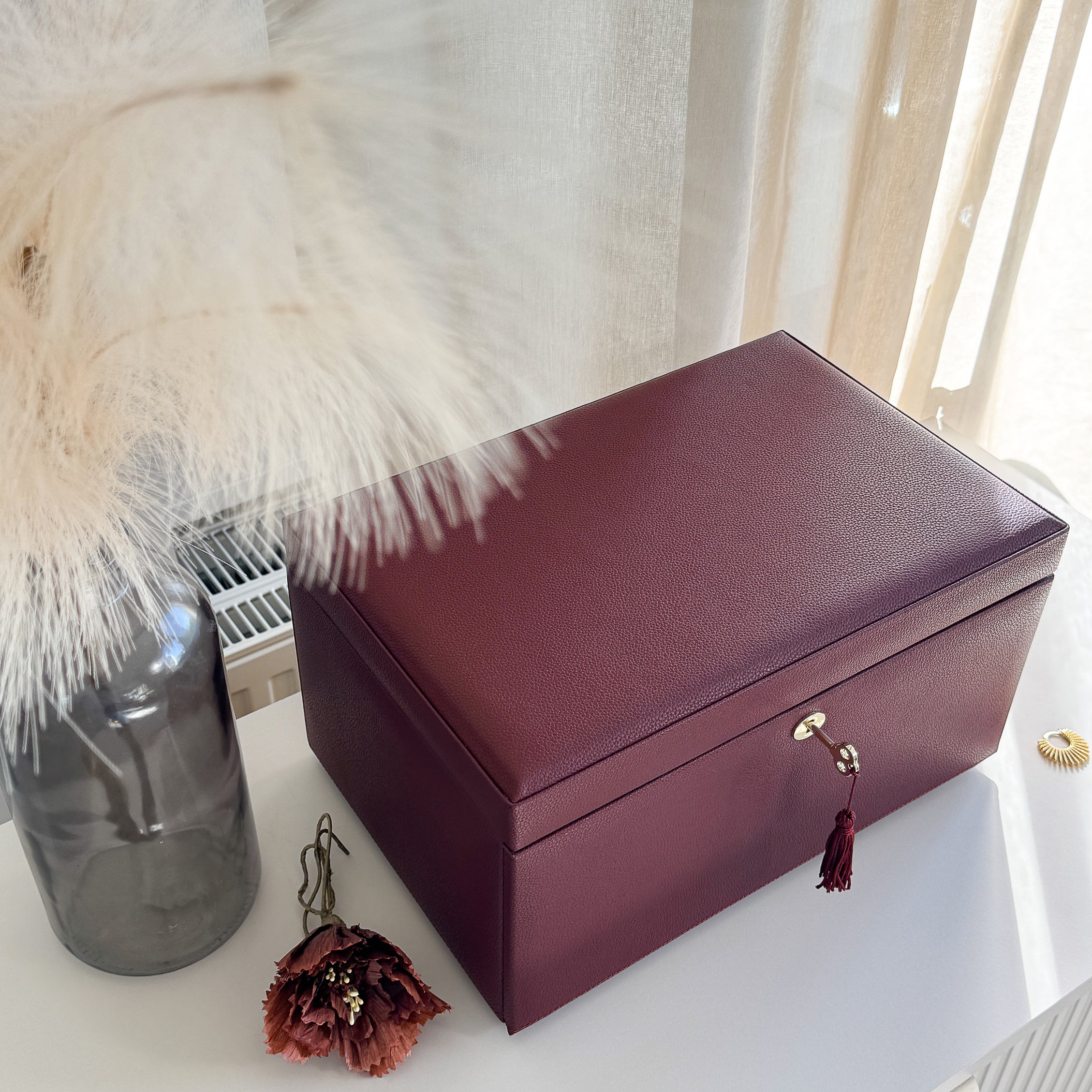 Grande boîte à bijoux en cuir bordeaux de la collection Vitoria. Vue fermée, posée sur une commode