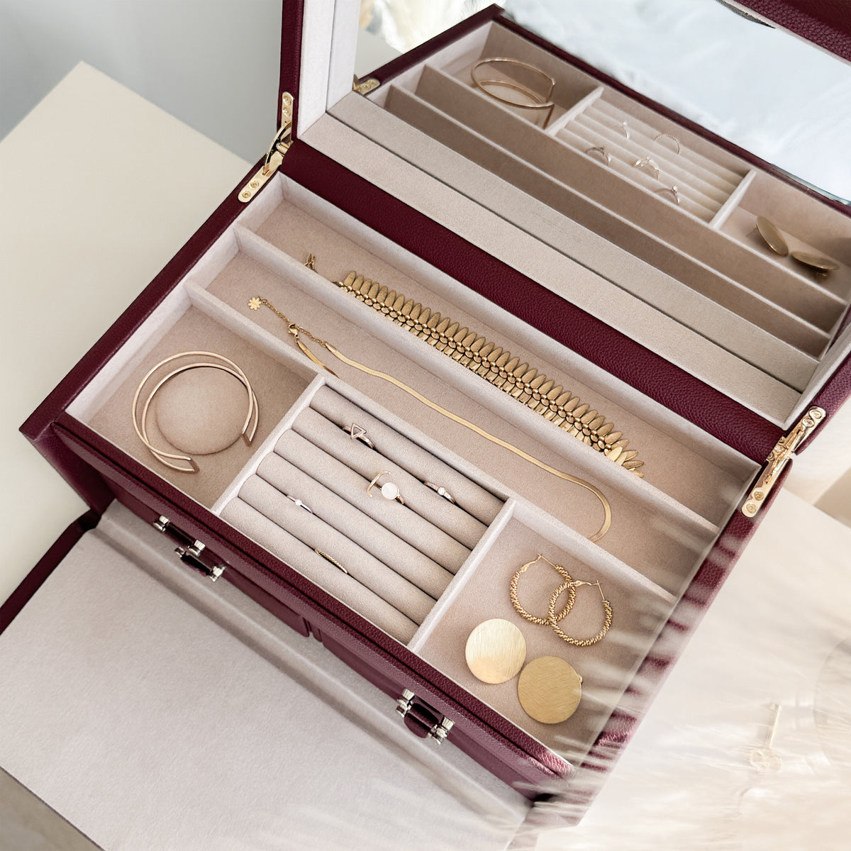 Grande boîte à bijoux en cuir bordeaux de la collection Vitoria. Vue ouverte, remplie de bijoux avec un zoom sur le compartiment supérieur