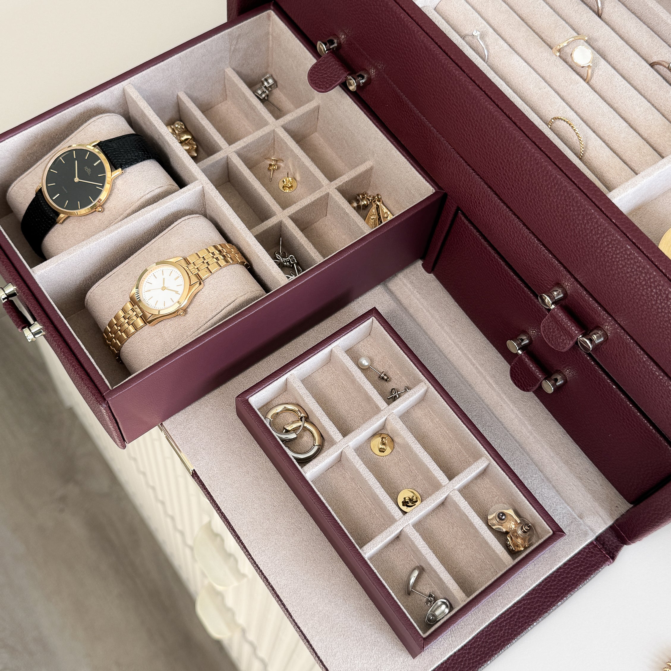 Grande boîte à bijoux en cuir bordeaux de la collection Vitoria. Vue ouverte, remplie de bijoux avec un zoom sur les tiroirs à bijoux