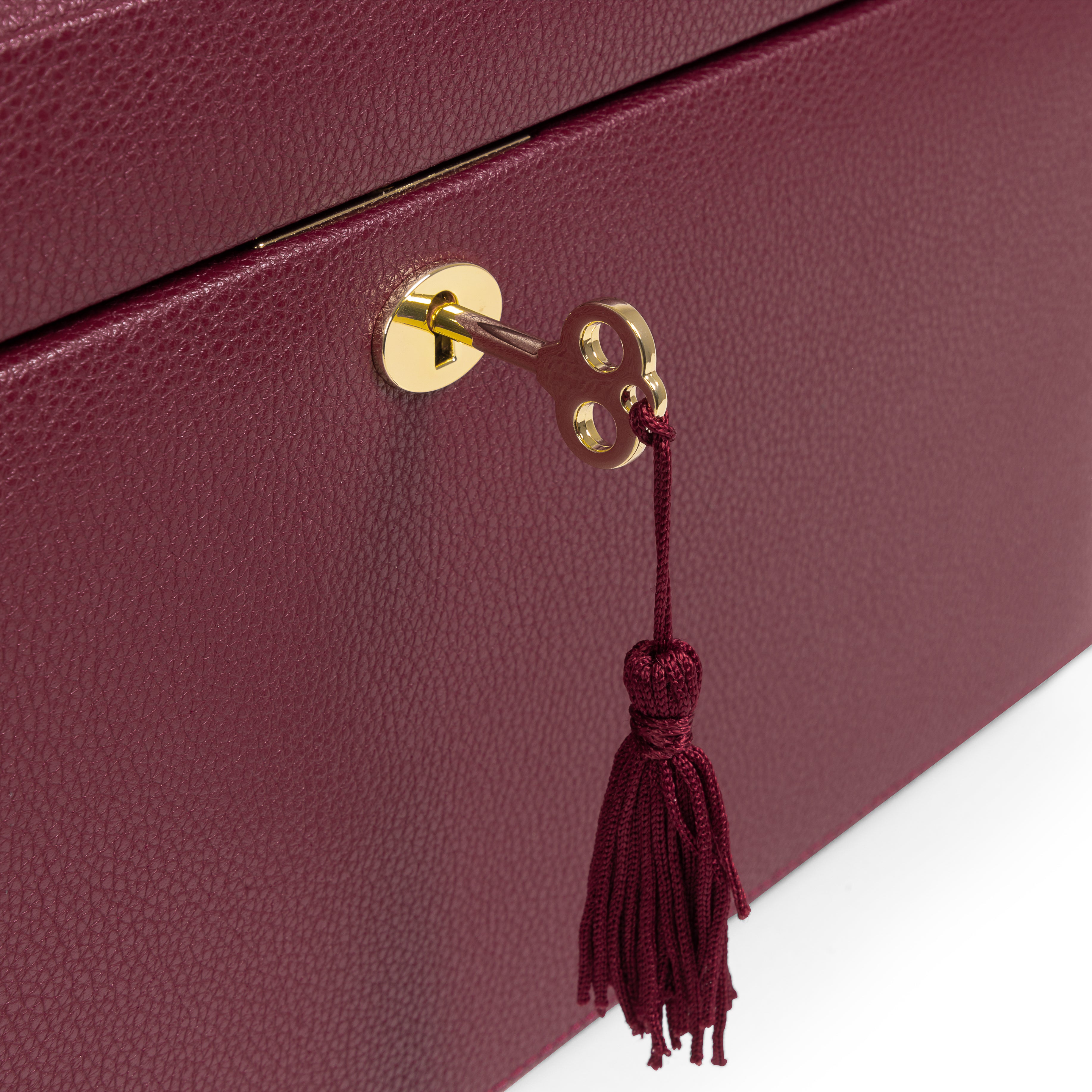 Grande boîte à bijoux en cuir bordeaux de la collection Vitoria. Zoom sur le fermoir doré et la clé avec son pompon. Fond blanc