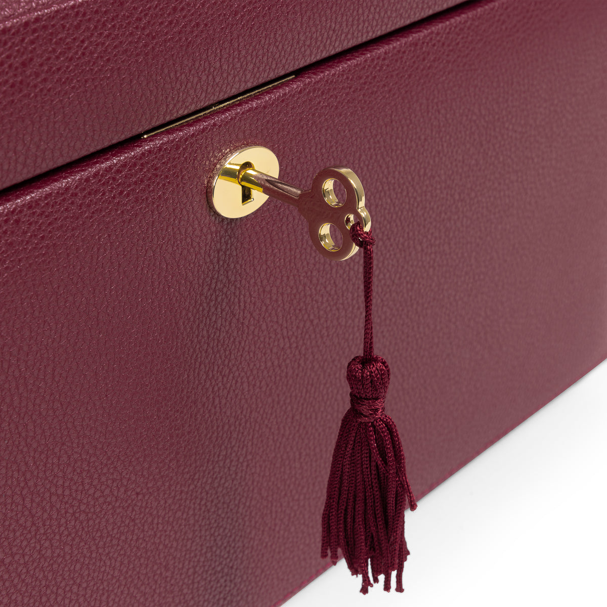 Grande boîte à bijoux en cuir bordeaux de la collection Vitoria. Zoom sur le fermoir doré et la clé avec son pompon. Fond blanc