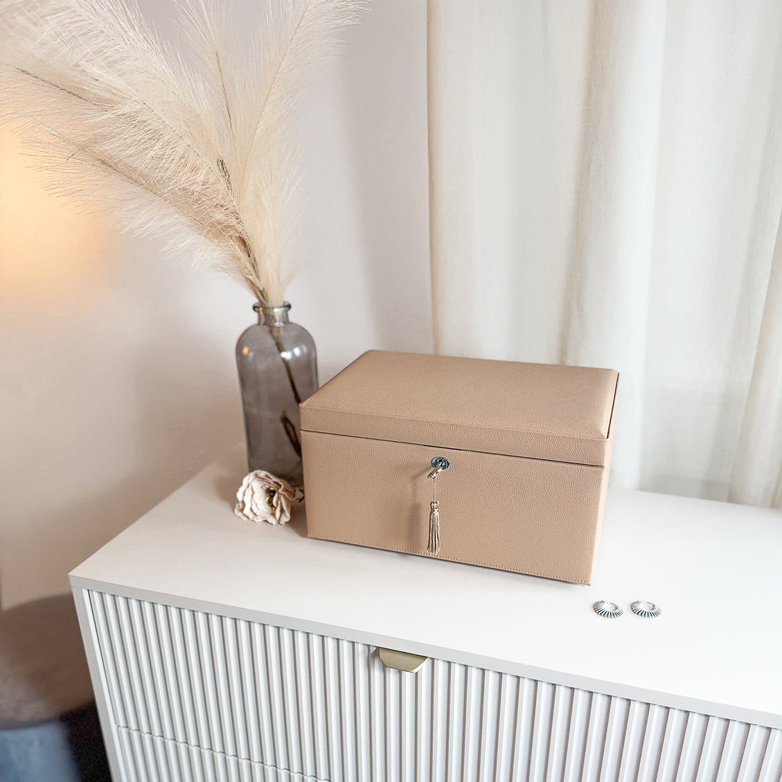 Grande boîte à bijoux en cuir cappuccino de la collection Vitoria. Vue fermée, posée sur une commode