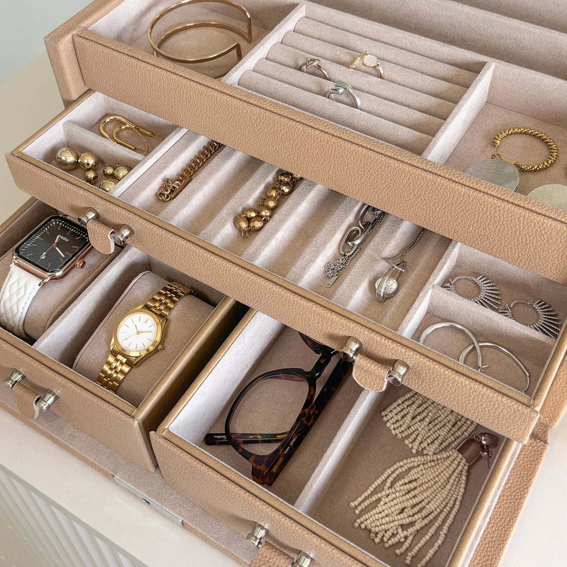Grande boîte à bijoux en cuir cappuccino de la collection Vitoria. Vue ouverte, remplie de bijoux