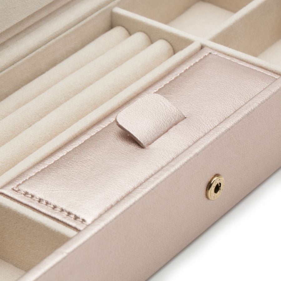 Gros plan sur une boîte à bijoux rose irisé avec compartiments et pouch intégré