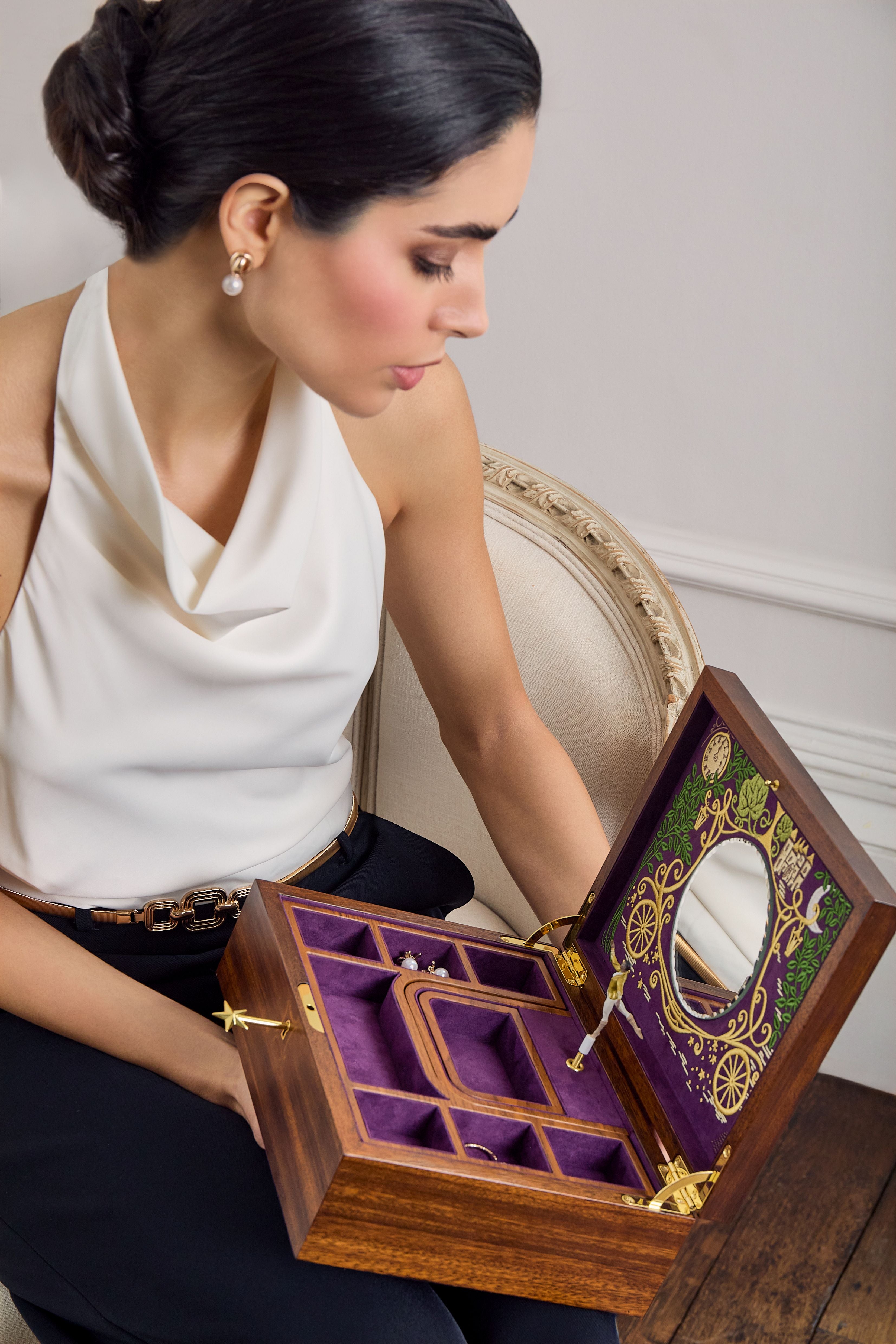 Femme élégante contemplant une boîte à bijoux en bois ouverte avec miroir, compartiments et intérieur en velours violet, issue de la collection Ballet de WOLF 1834.