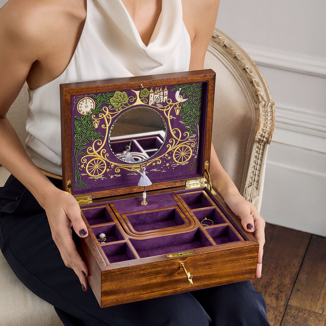 Femme élégante tenant une boîte à bijoux en bois ouverte avec miroir, compartiments et intérieur en velours violet, issue de la collection Ballet de WOLF 1834.