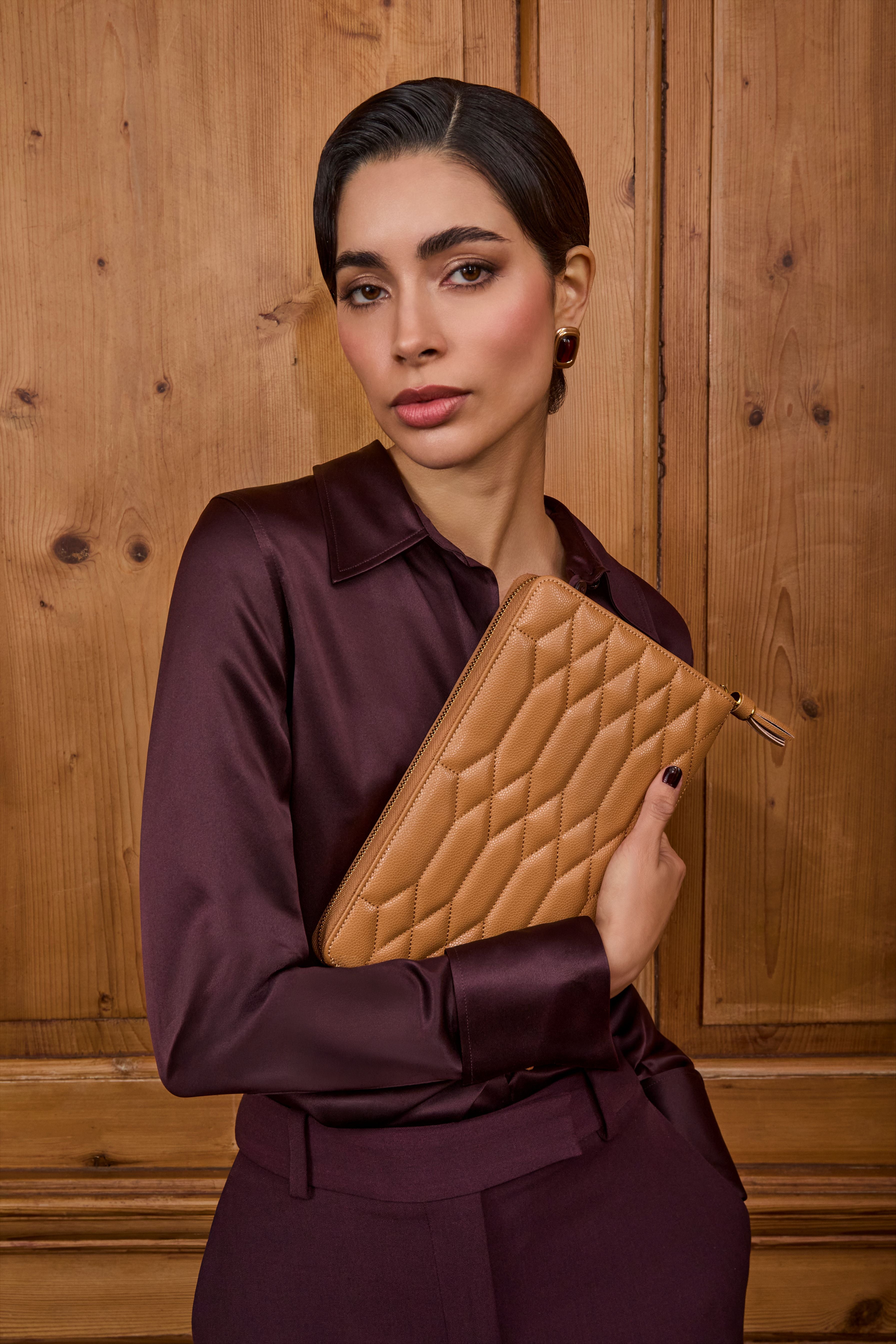Femme élégante tenant une pochette à bijoux matelassée couleur caramel, issue de la collection Lauren de WOLF 1834.