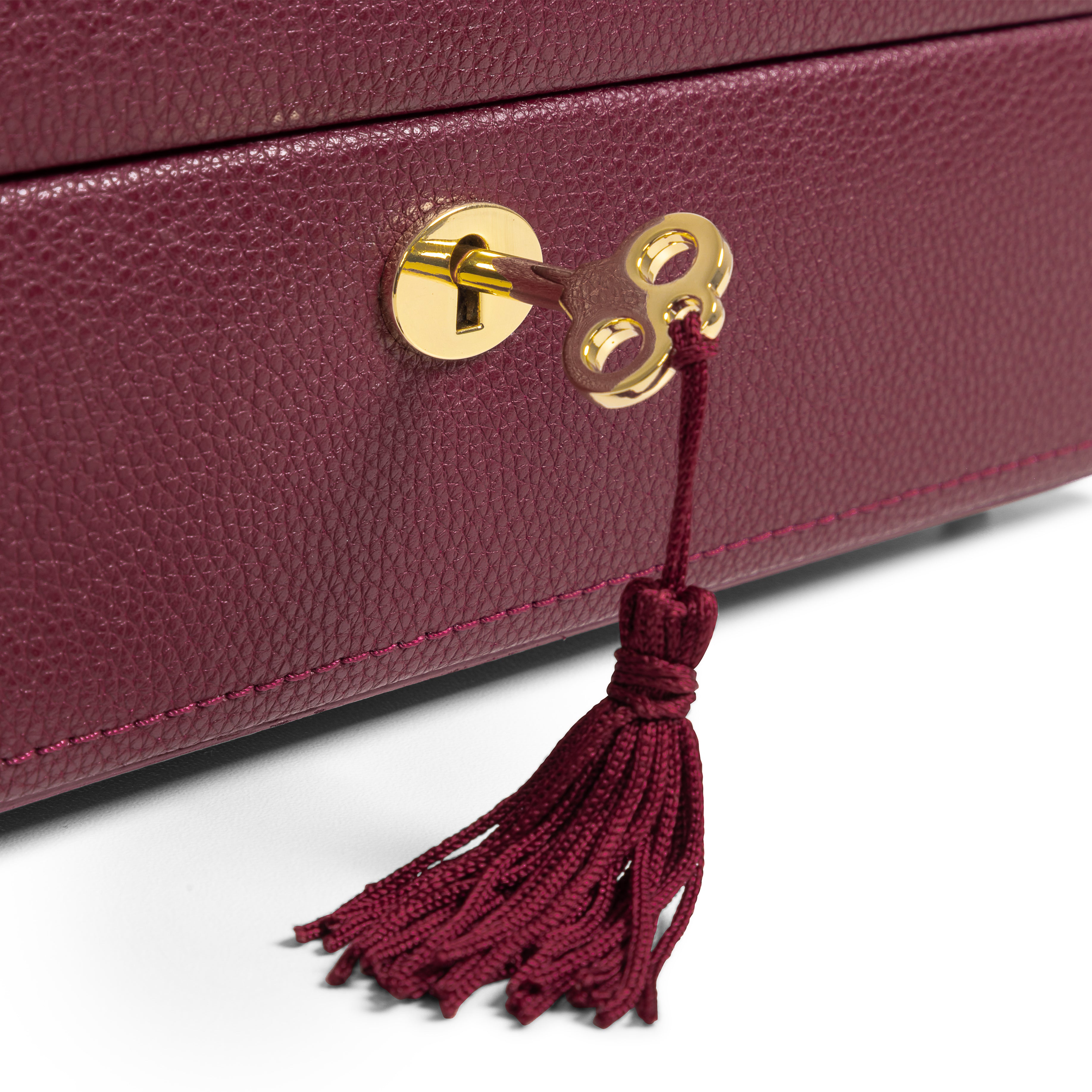 Boîte à bijoux en cuir bordeaux de la collection Vitoria. Zoom sur la serrure dorée et la clé à pompon. Fond blanc