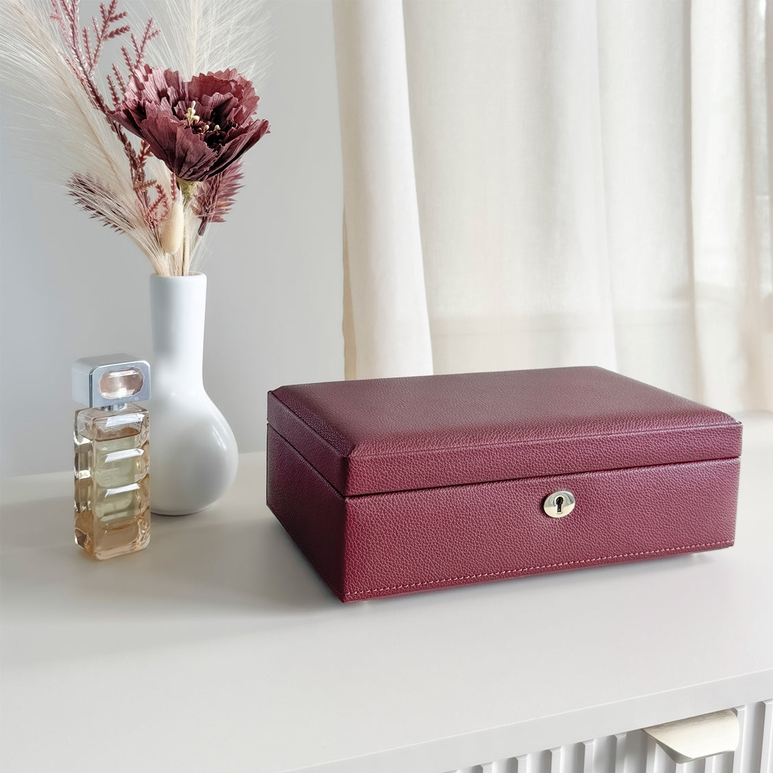 Boîte à bijoux en cuir bordeaux de la collection Vitoria. Vue fermée, posée sur une commode