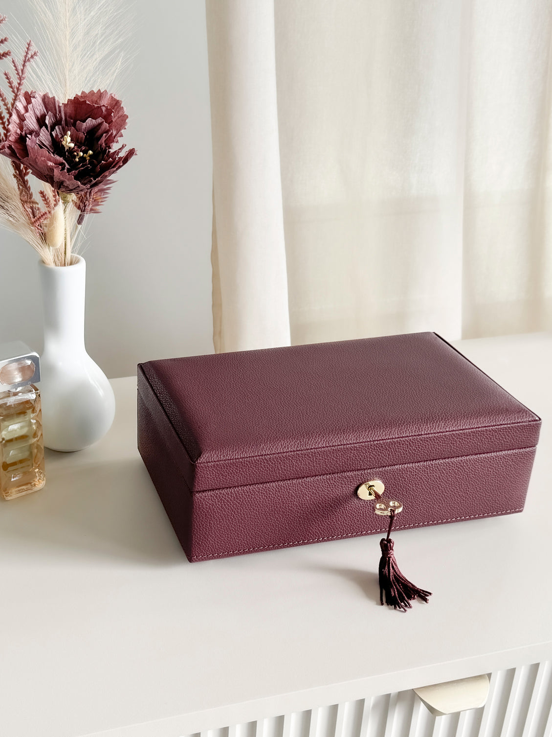Boîte à bijoux en cuir bordeaux de la collection Vitoria. Vue fermée, posée sur une commode