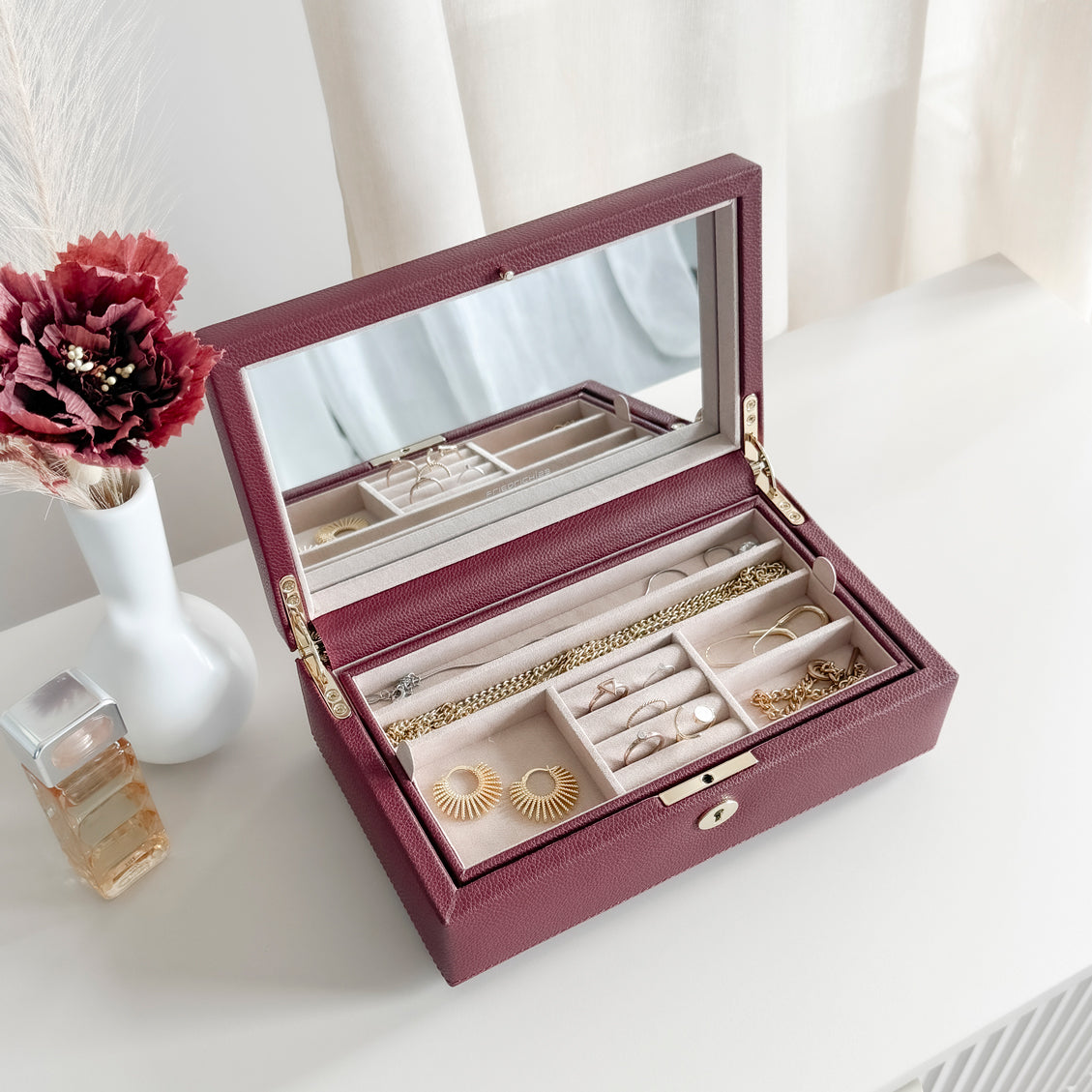 Boîte à bijoux en cuir bordeaux de la collection Vitoria. Vue ouverte remplie de bijoux. Le compartiment intérieur est rangé dans la boîte