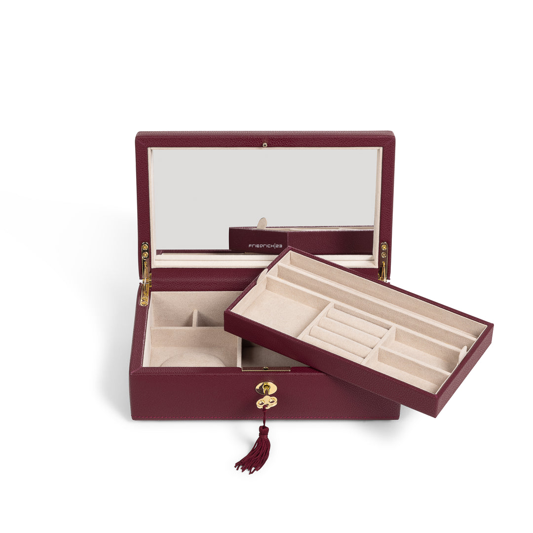 Boîte à bijoux en cuir bordeaux de la collection Vitoria. Vue ouverte, avec compartiment posé en travers et clé dorée insérée dans la serrure. Fond blanc