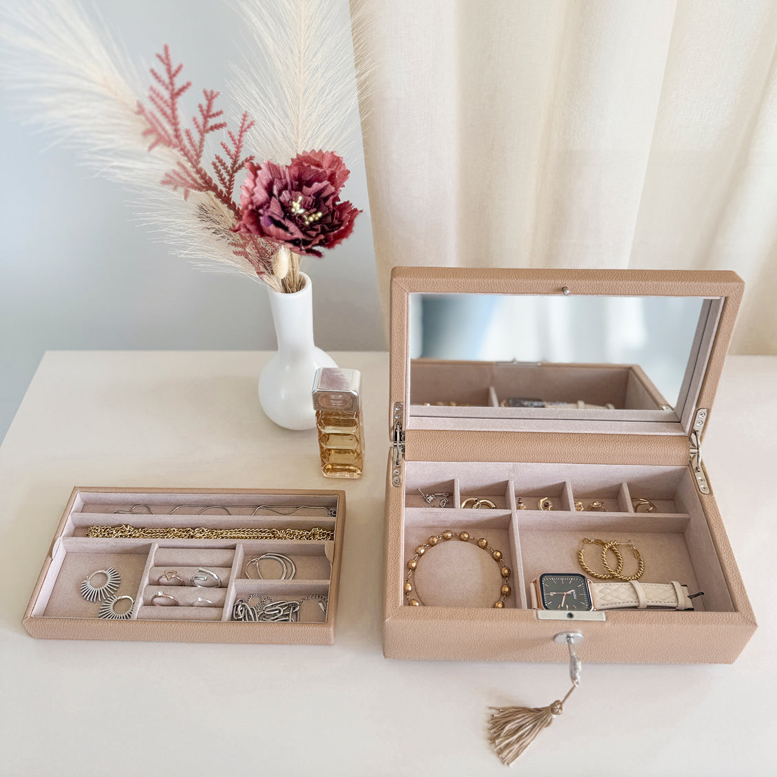 Boîte à bijoux en cuir cappuccino de la collection Vitoria. Vue ouverte, posée sur une commode avec le compartiment intérieur sorti de la boîte et rempli de bijoux