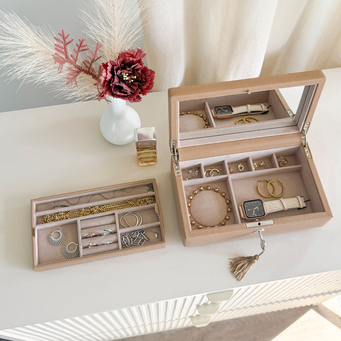Boîte à bijoux en cuir cappuccino de la collection Vitoria. Vue ouverte de haut, posée sur une commode avec le compartiment intérieur sorti de la boîte et rempli de bijoux