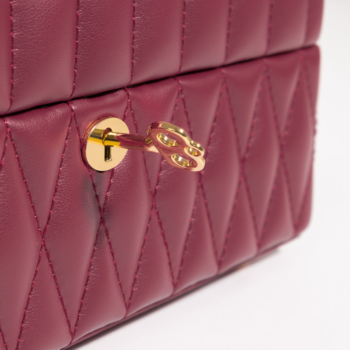 Boîte à bijoux matelassé Saphira bordeaux. Zoom sur le revêtement matellassé et la serrure / clé dorée