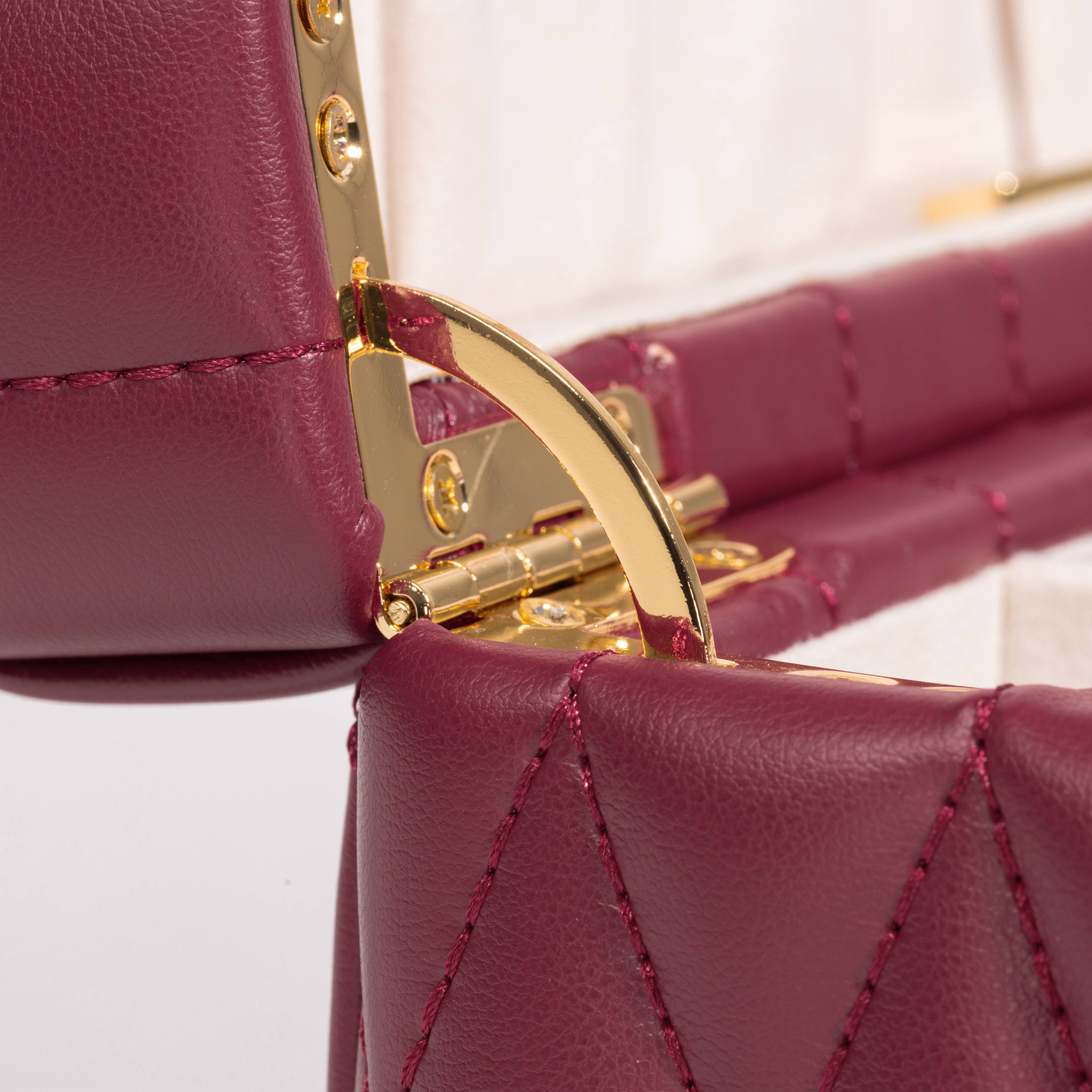 Boîte à bijoux matelassé Saphira bordeaux. Zoom sur le revêtement matellassé et la charnière dorée