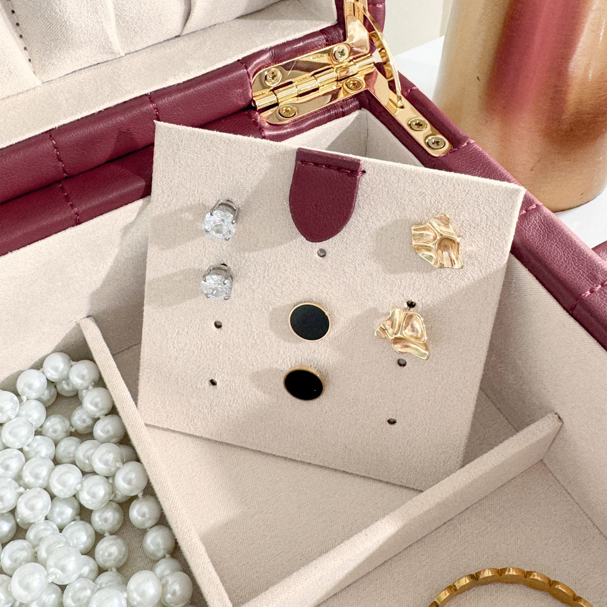 Boîte à bijoux matelassé Saphira bordeaux. Zoom sur le support à boucles d'oreille, rempli de boucles d'oreille