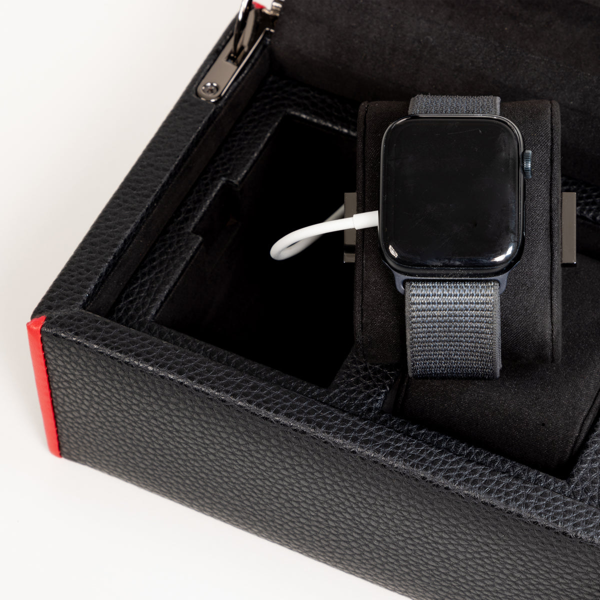 Boîte à montre vitrée en cuir noir avec passepoil rouge Maranello, cinq emplacements. Zoom sur un coussin de support avec montre connectée