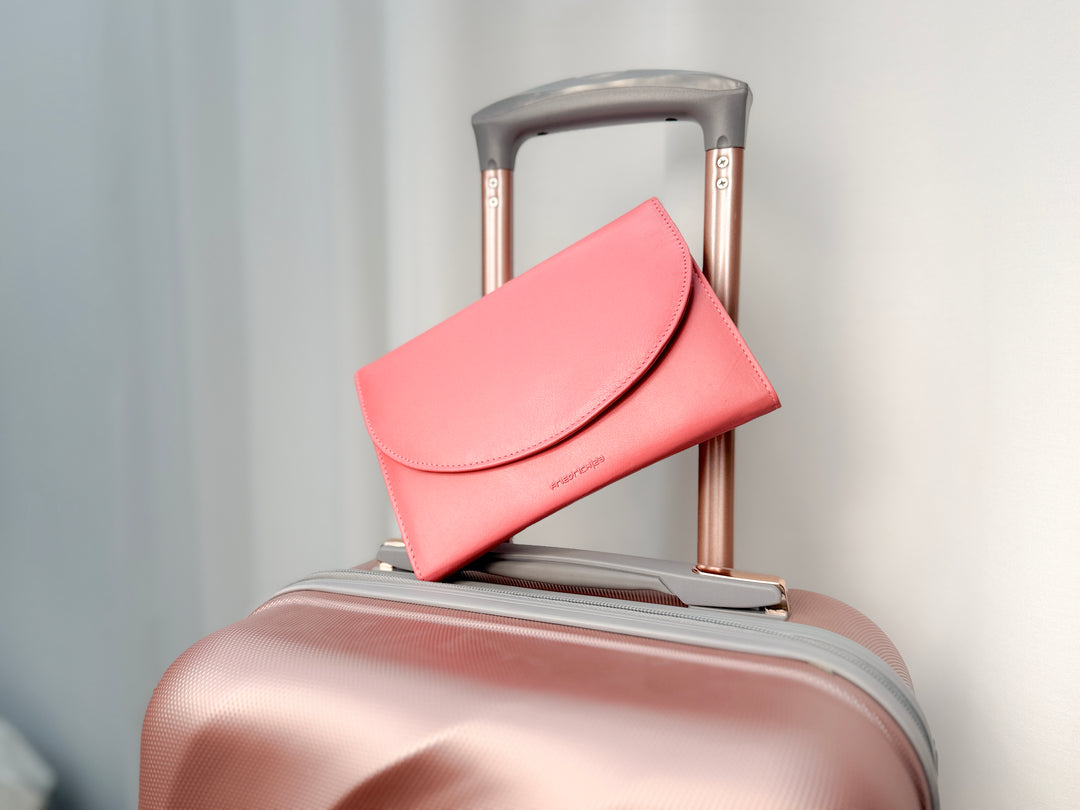 Grand étui à bijoux de voyage en cuir véritable Sienna, rose corail, vue fermé, de face, posé sur une valise de couleur rose irisé