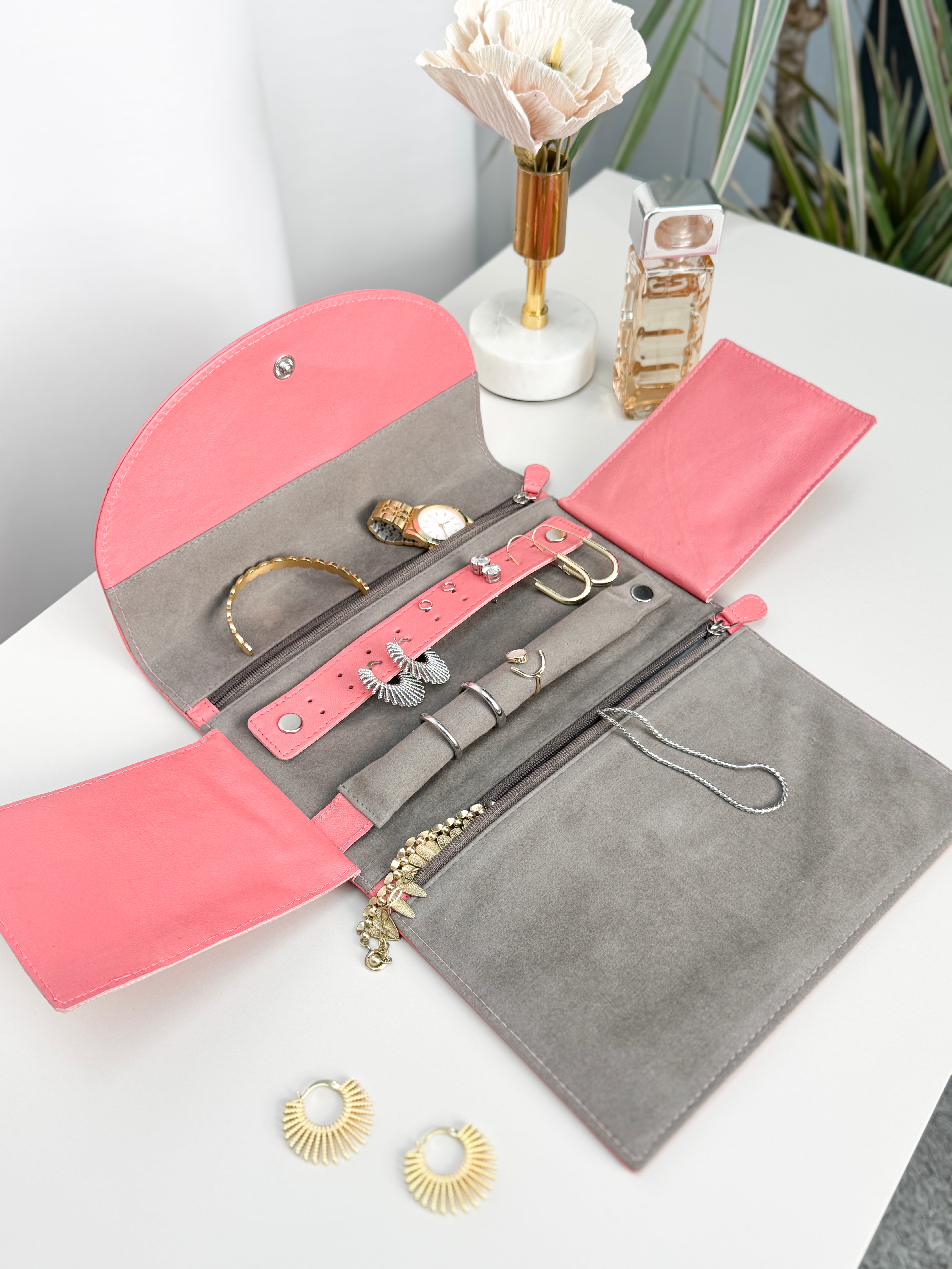 Grand étui à bijoux de voyage en cuir véritable Sienna, rose corail, vue ouverte, posée sur une table et remplie de bijoux