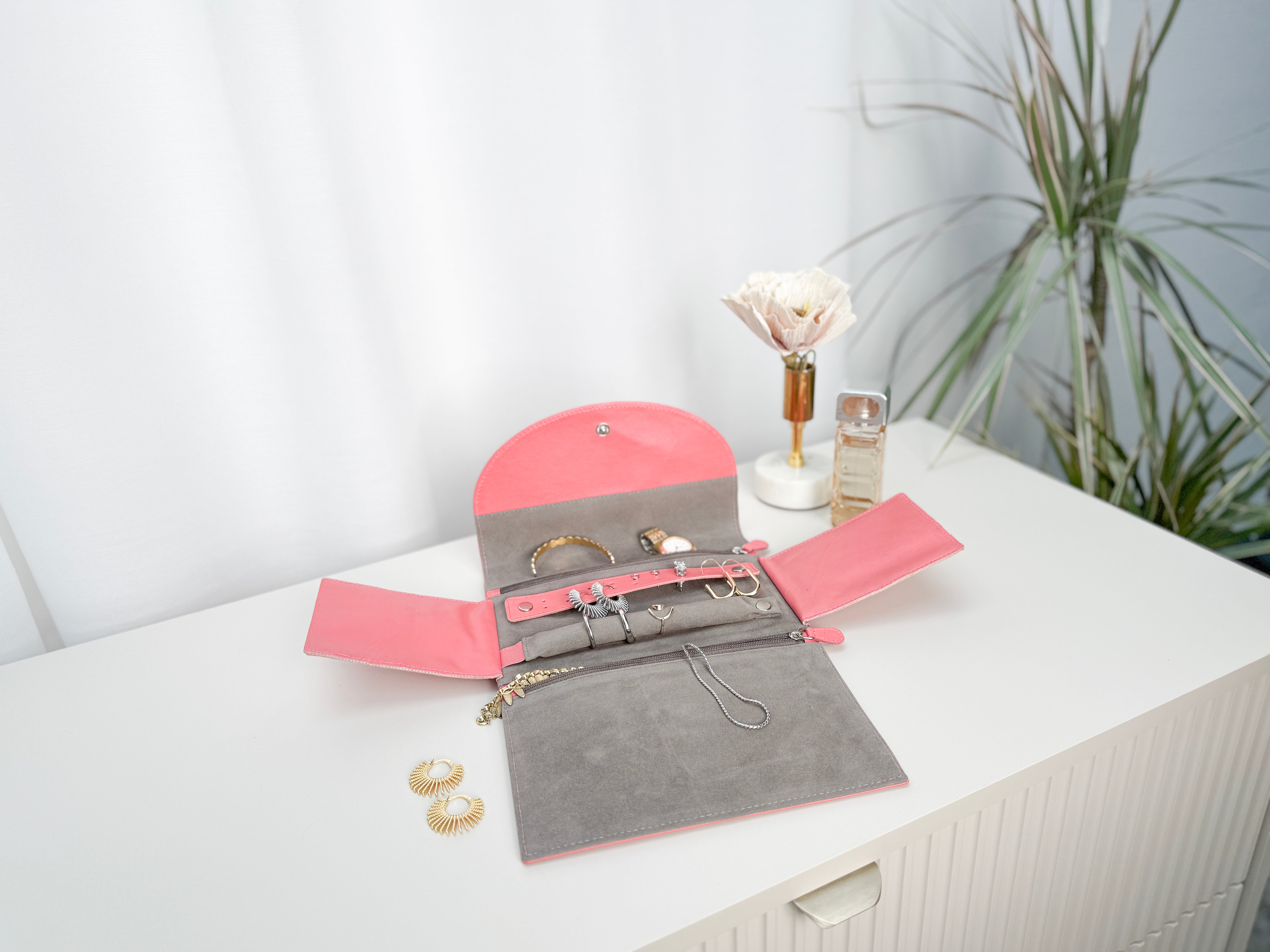 Grand étui à bijoux de voyage en cuir véritable Sienna, rose corail, vue ouverte, posée sur une table et remplie de bijoux