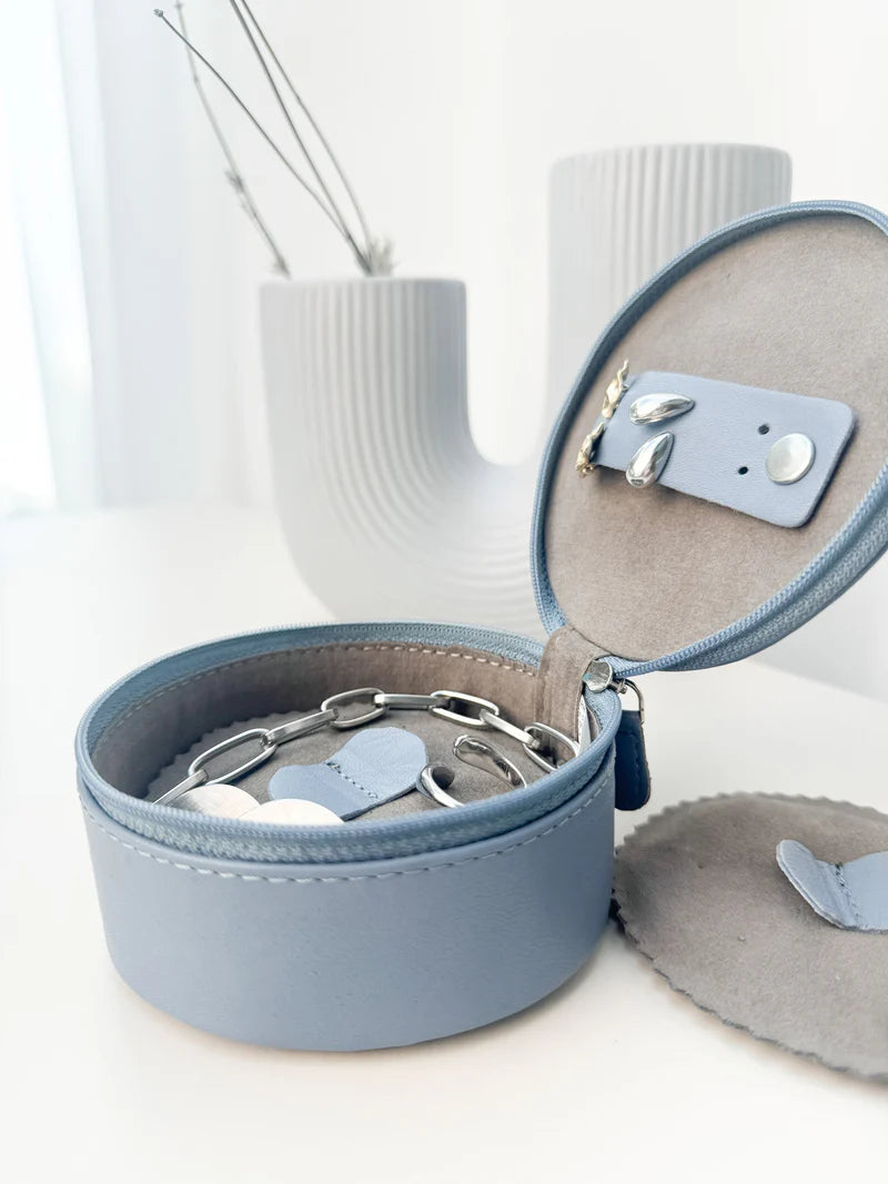 Mini boite à bijoux ronde en cuir véritable Sienna, bleu clair, vue ouverte, posée sur une table à coté d'un vase blanc