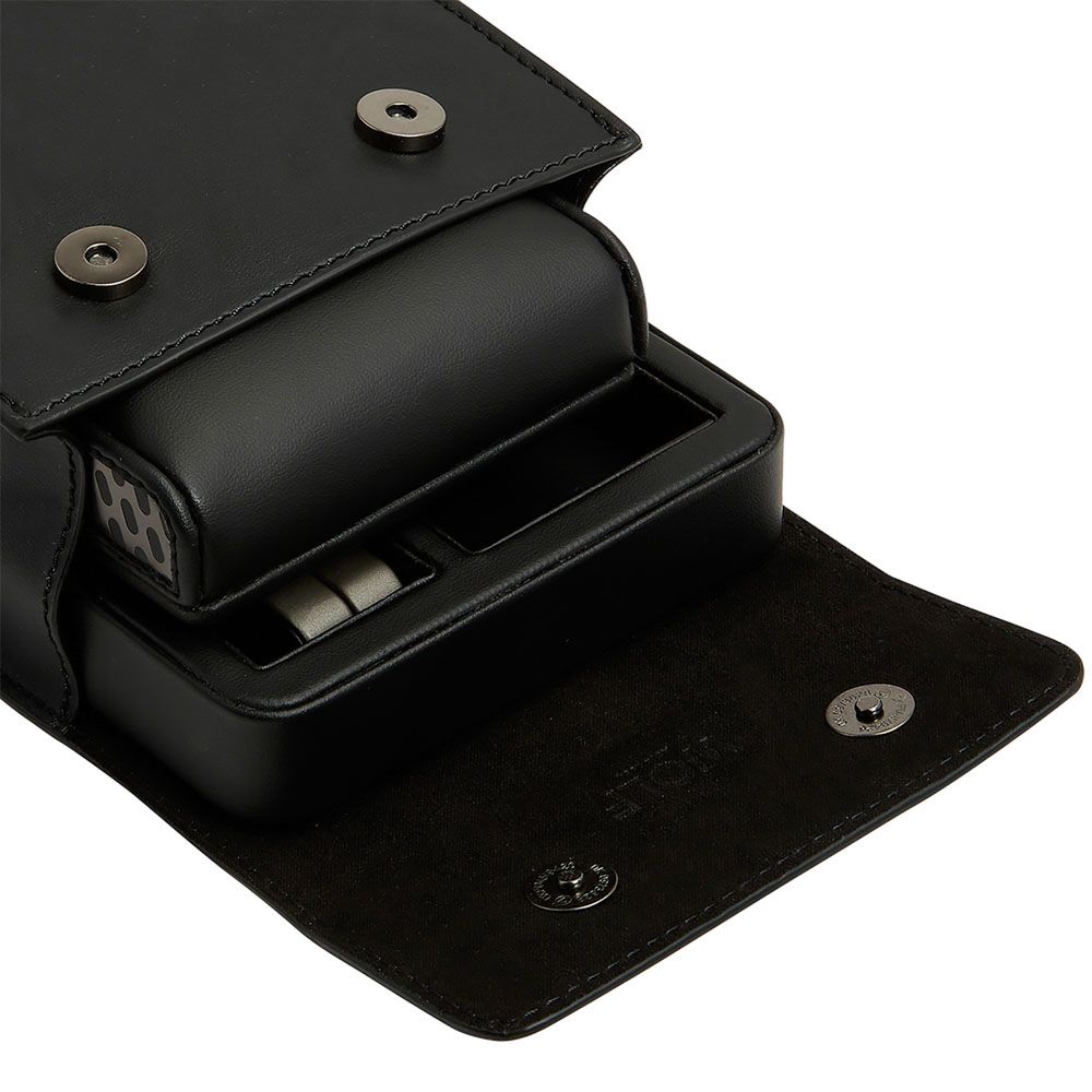Étui de voyage en cuir noir pour montre, avec rabat à boutons-pression ouvert laissant apparaître un coussin rembourré et une base de rangement intégrée
