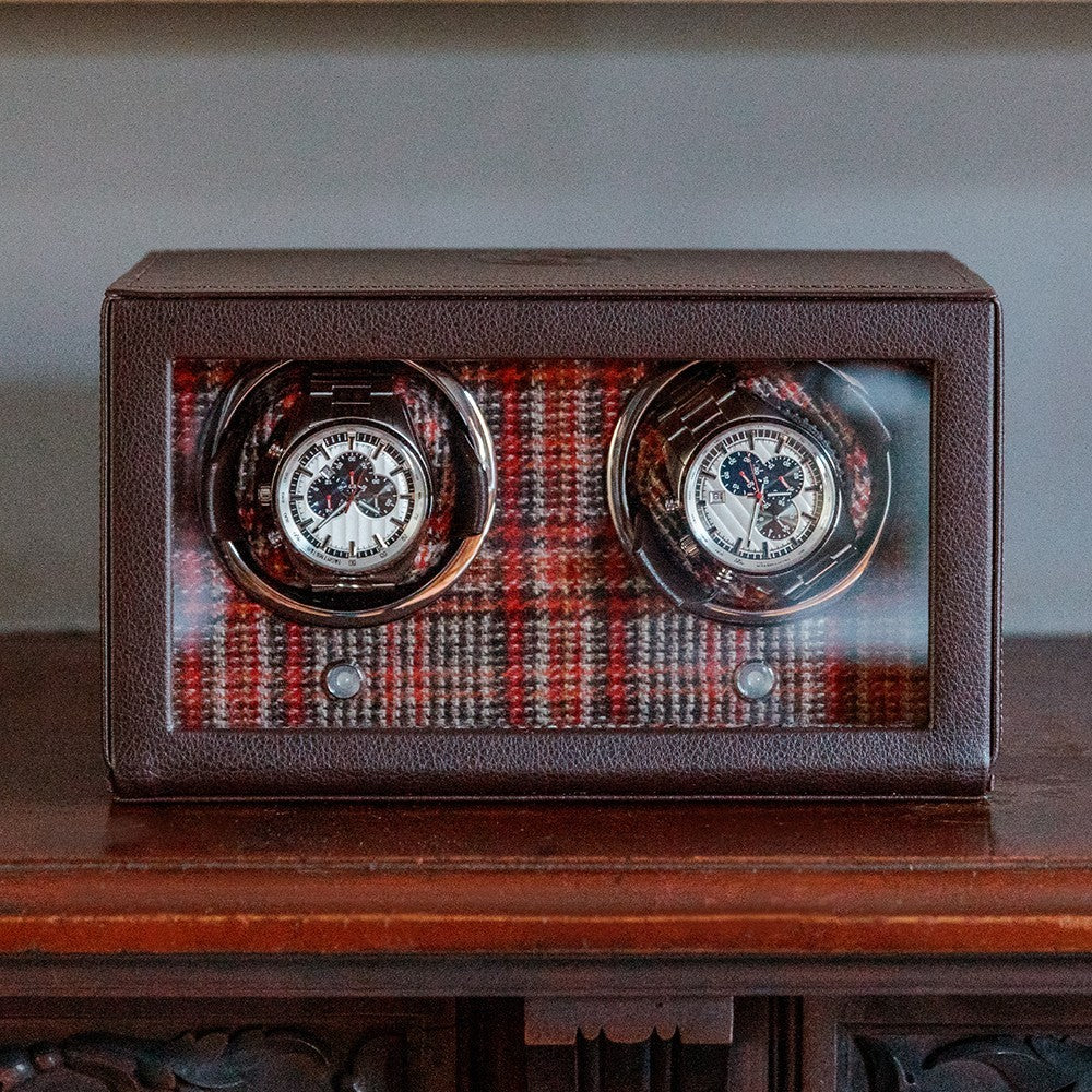 Remontoir à montres en cuir marron avec façade vitrée et fond intérieur motif tartan rouge, contenant deux montres