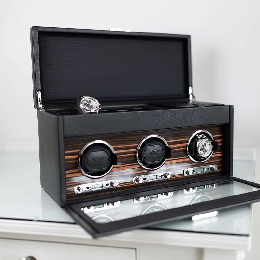 Remontoir à montre WOLF en cuir noir avec façade vitrée et intérieur en bois d’ébène, présenté ouvert avec trois modules rotatifs